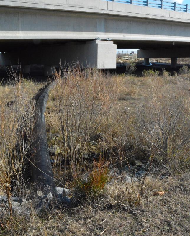 The pipe exits the culvert and winds its way under the Charles W. Cullen Bridge before crossing the dune.